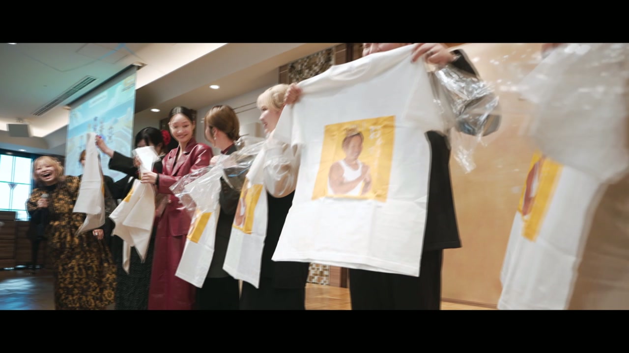 顔写真入りのTシャツを掲げるスタッフたち