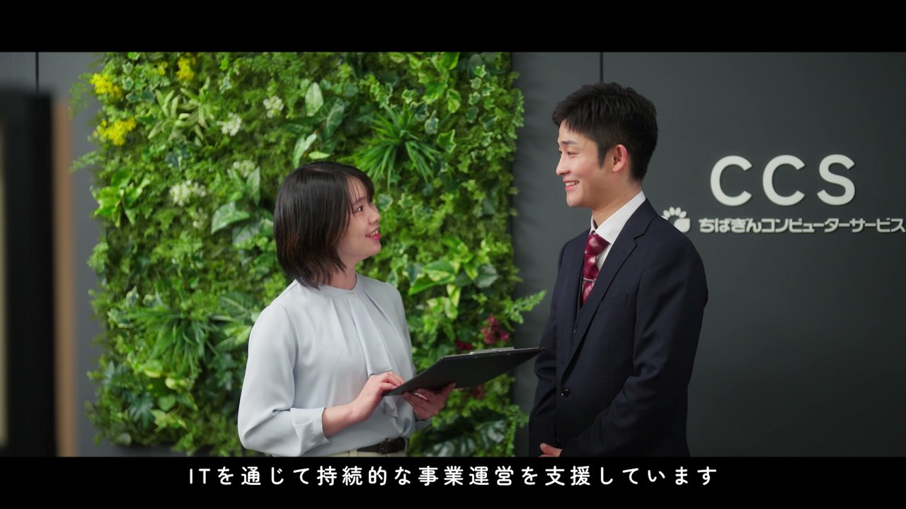 グリーンウォールの前で打合せをする社員 ／「ITを通じて持続的な事業運営を支援しています」
