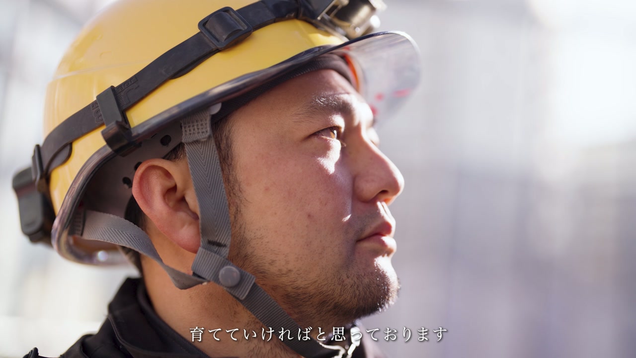 ヘルメット姿で遠くを見つめる電気工事士 ／「育てていければと思っております」