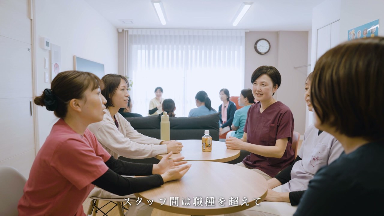 テーブルを囲んで話すスタッフ ／「スタッフ間は職種を超えて」