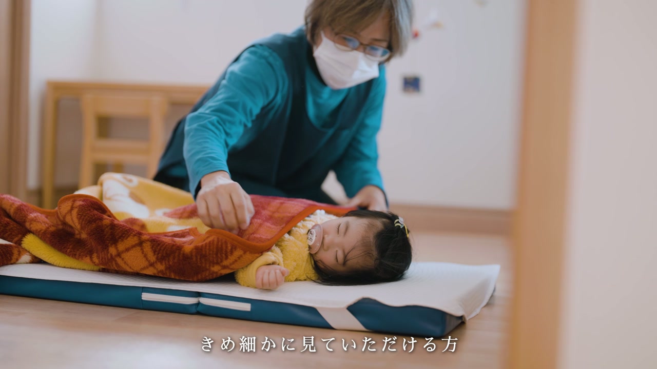 お昼寝するお子さんに寄り添う保育士 ／「きめ細かに見ていただける方」