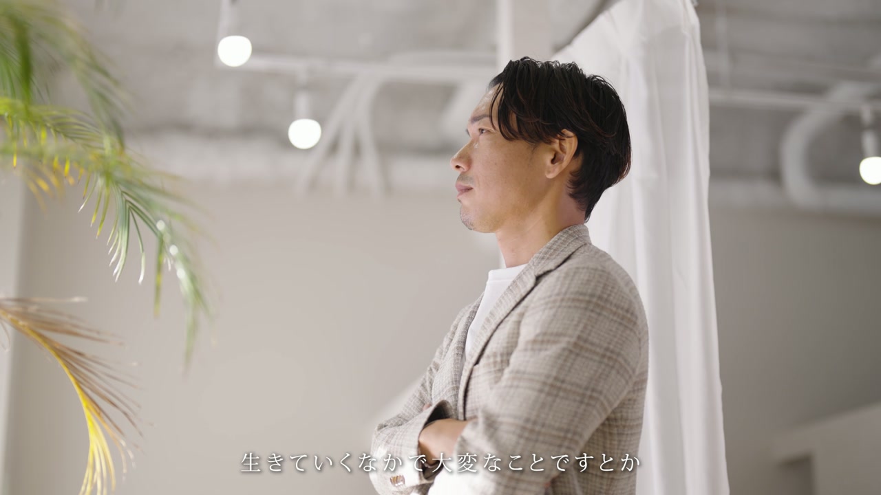窓辺に立ち、遠くを見つめる多田社長