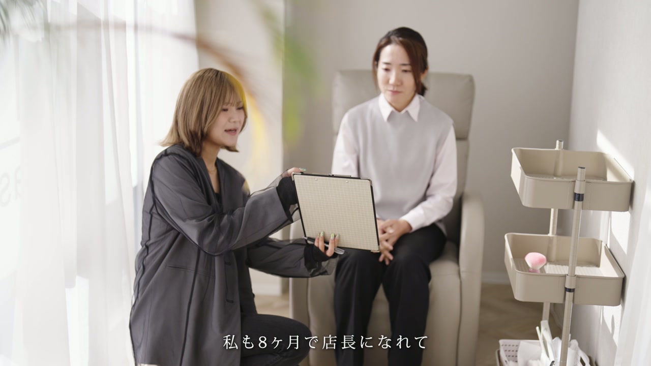 タブレットを手に後輩へ話しかけるスタッフ ／「私も8ヶ月で店長になれて」